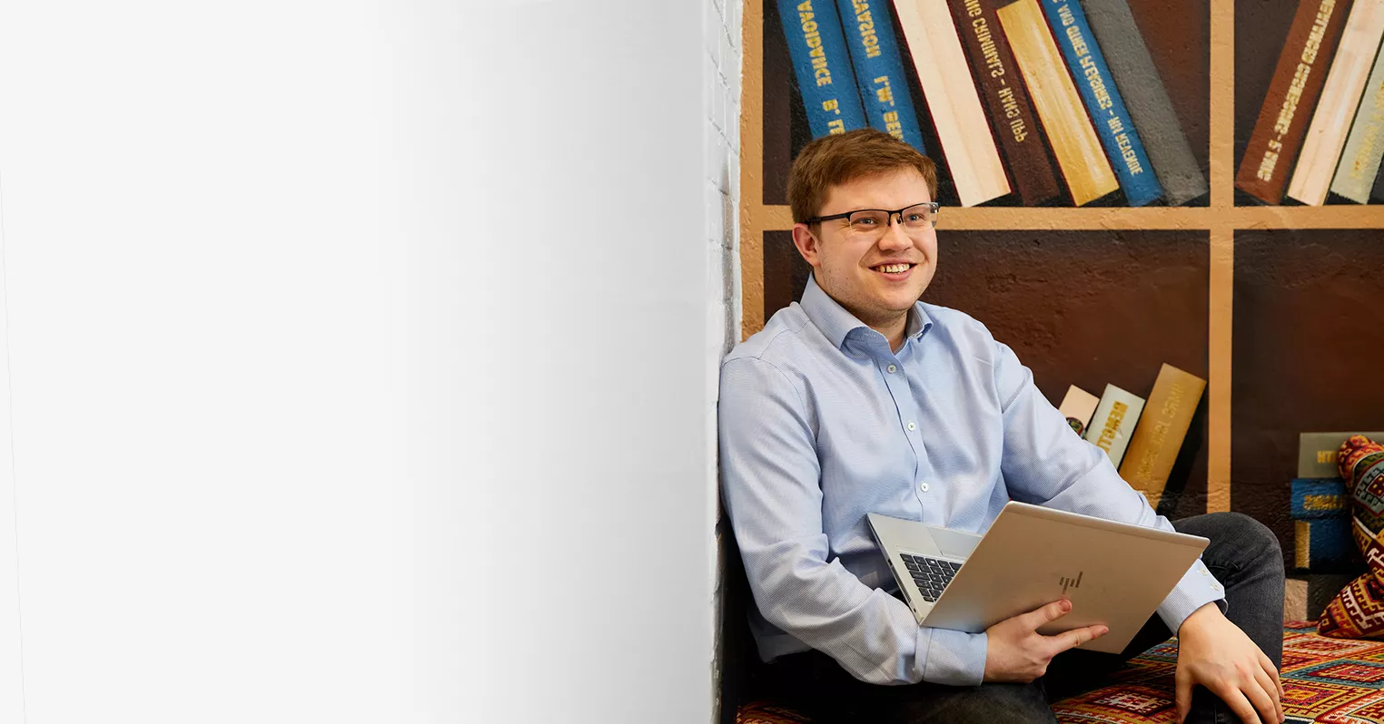 A smiling man in glasses holding a laptop