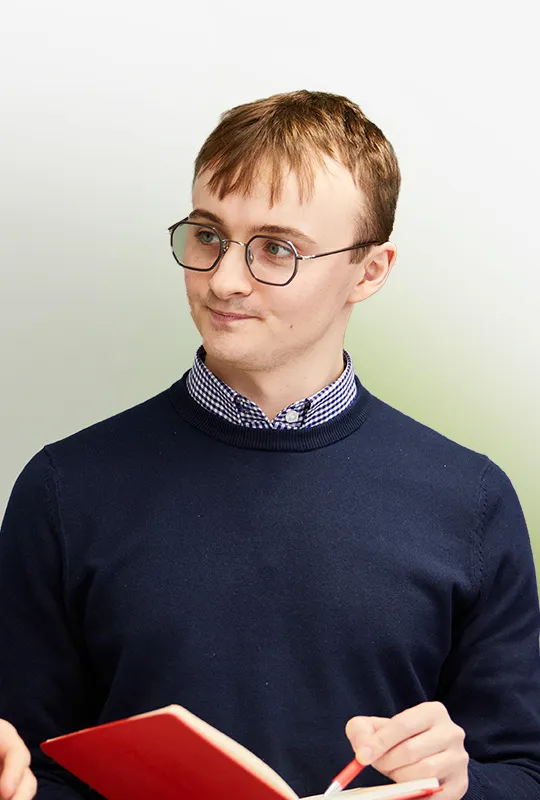 A man in glasses holding a red book