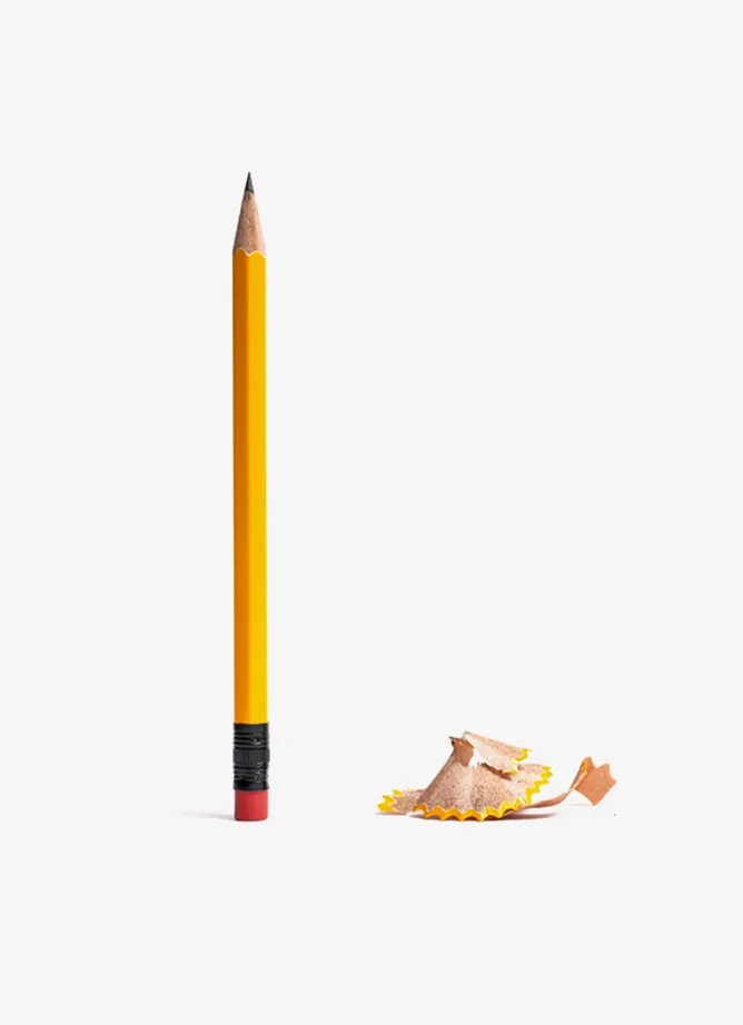 A yellow pencil stood vertically, next to a pile of pencil shavings