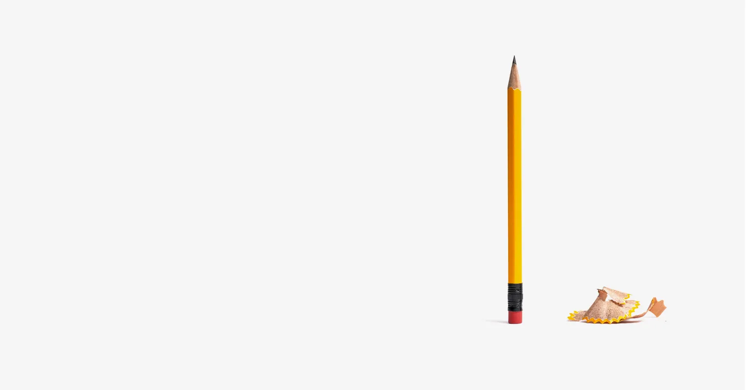 A yellow pencil stood vertically, next to a pile of pencil shavings